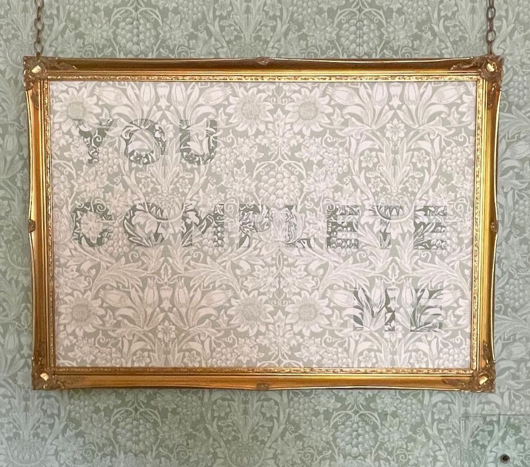You Complete Me piece of embroidery art. The piece is William Morris patterned wallpaper with You Complete Me embroidered on it in colours that match the background.