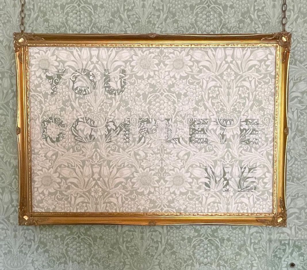 You Complete Me piece of embroidery art. The piece is William Morris patterned wallpaper with You Complete Me embroidered on it in colours that match the background. 