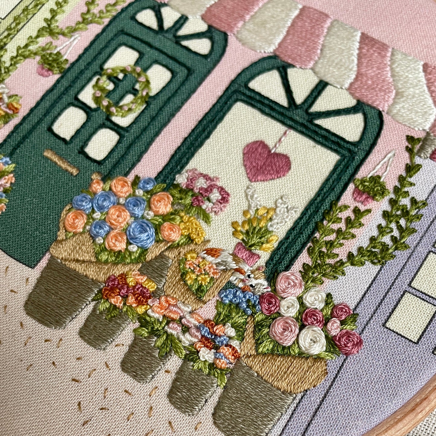 Embroidery hoop with floral design and heart, on a pink background