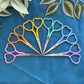 Set of colorful heart-shaped scissors on a blue fabric background with leaves.