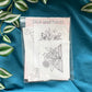 Packaging of Stick and Stitch embroidery kit placed on a blue fabric with leaf accents, displaying the brand name and contents of the package.