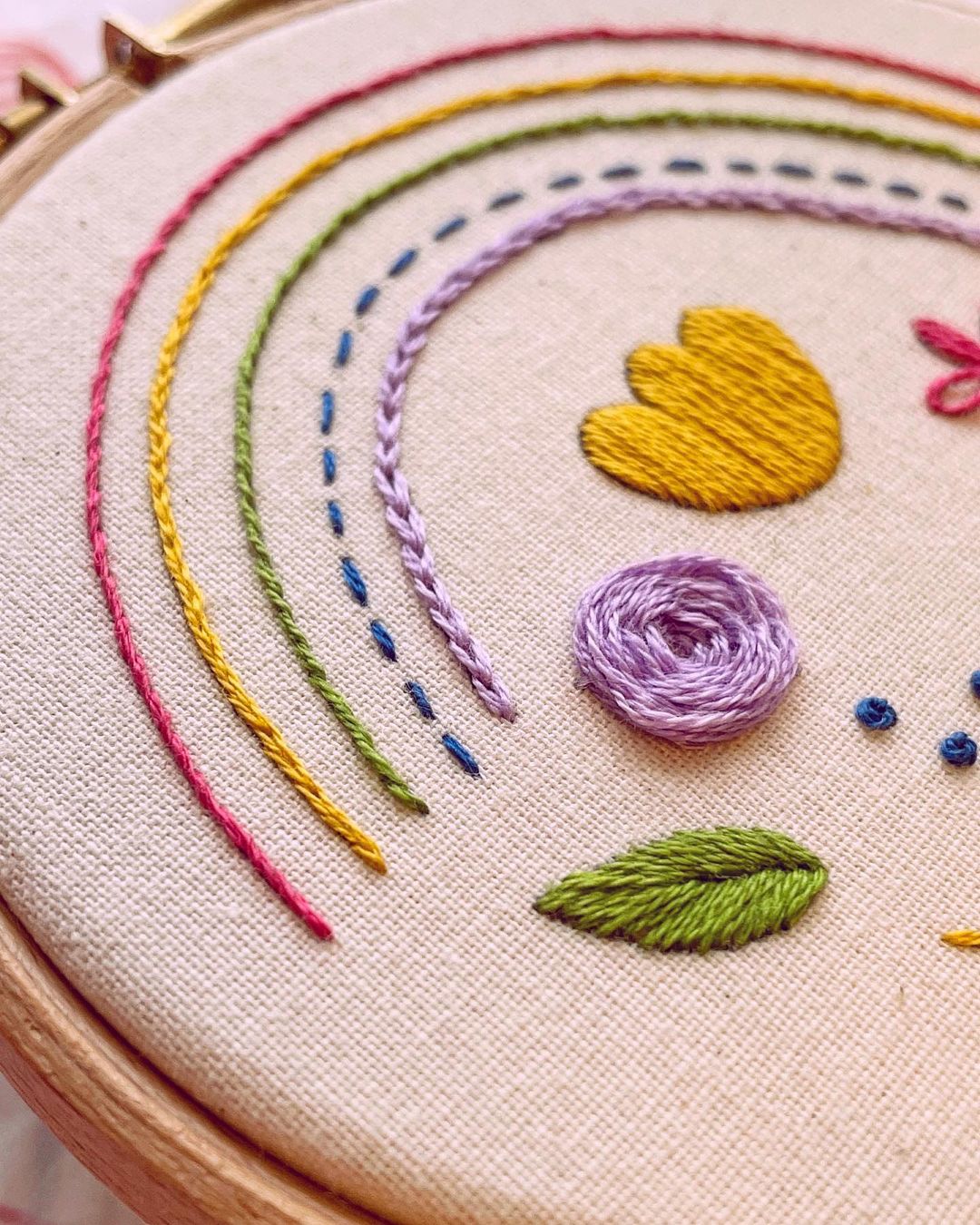 Close up of finished Wimperis Embroidery sampler kit showing embroidered rainbow and flowers